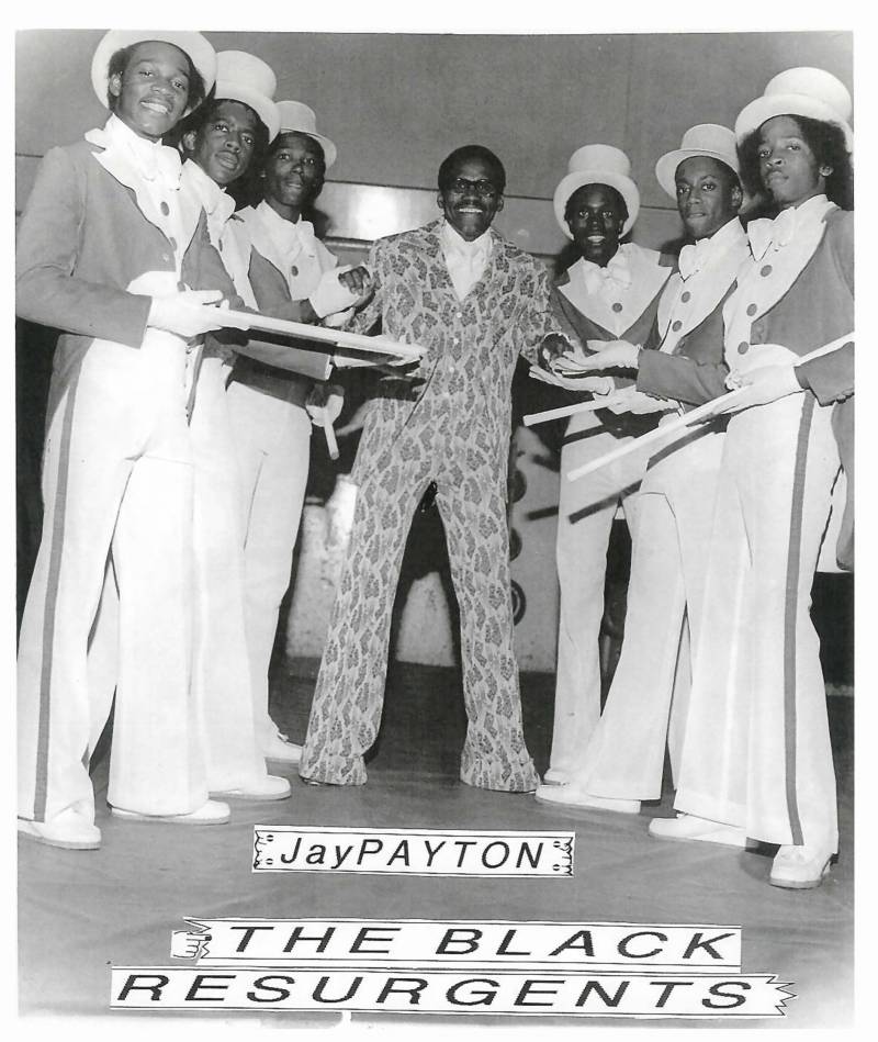 The Black Resurgents form a semi circle around TV host Jay Patton and post for a photo