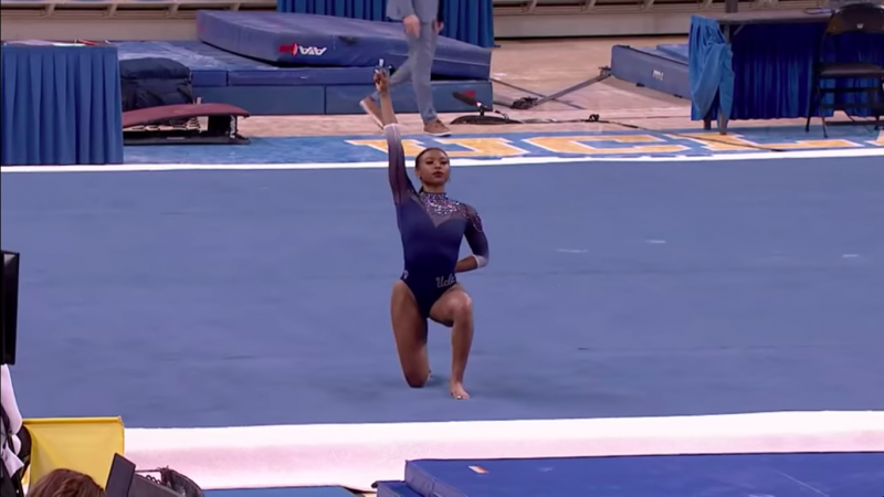 UCLA gymnast Nia Dennis proudly holds her fist aloft at the start of her now-viral 'Black Excellence' floor routine.