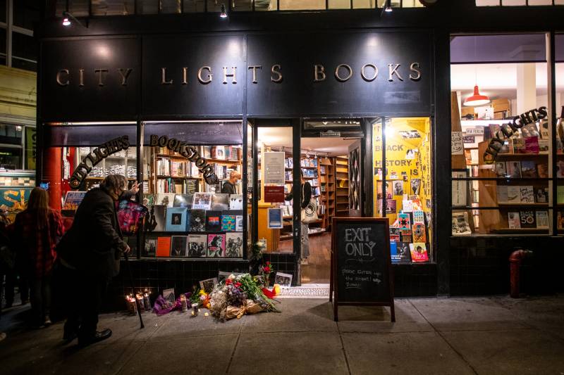 Flowers, candles and photos of Lawrence Ferlinghetti are left outside of City Lights Books on Feb. 23, 2021.
