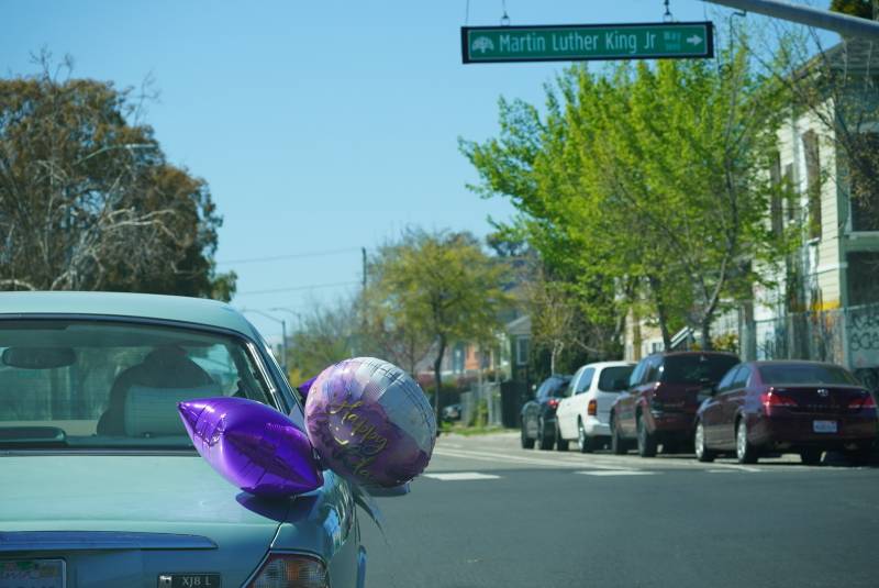 A car celebrating Marcella Hubbard's 100th birthday crosses Martin Luther King Jr. Way in Oakland.