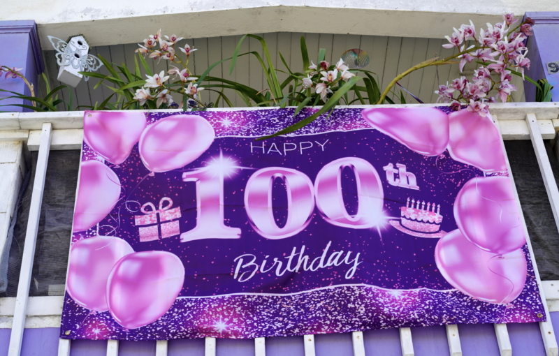 A purple "Happy 100th Birthday" banner mounted on the front of Mrs. Hubbard's house 