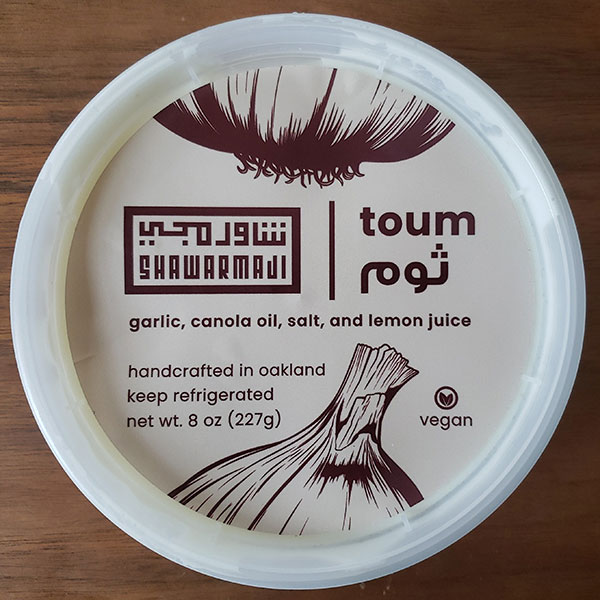 A tub of toum from Shawarmaji; the label lists the ingredients: garlic, canola oil, salt, lemon juice