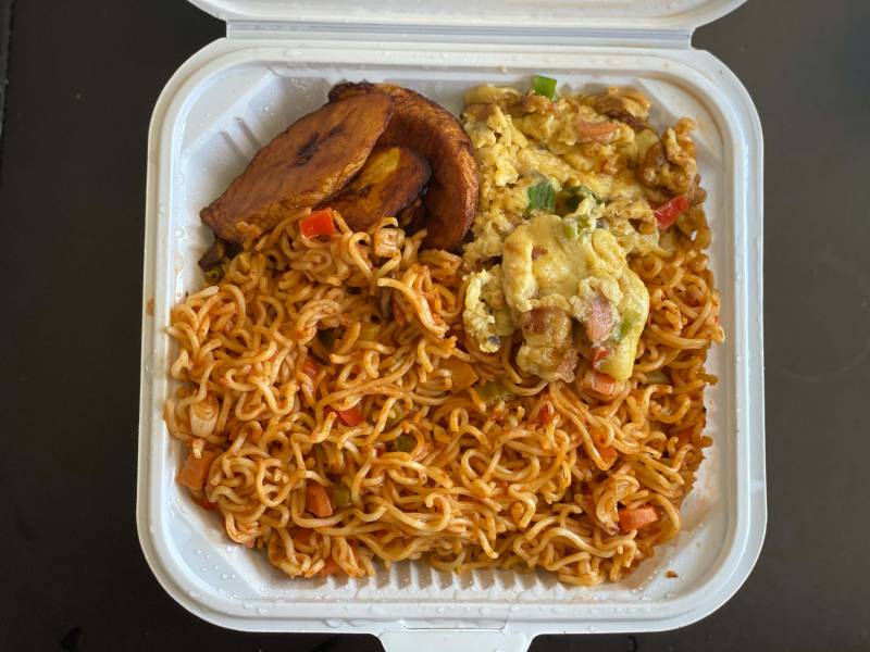 Overhead view of jollof Indomie: Indomie instant noodles tossed with vegetables and topped with plantains and scrambled egg