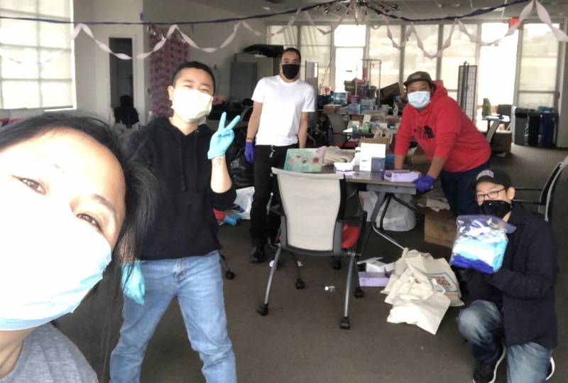 Volunteers with masks and gloves smile for a selfie.