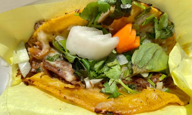 Closeup of a Vietnamese taco, with stewed beef and pickled carrot and daikon.