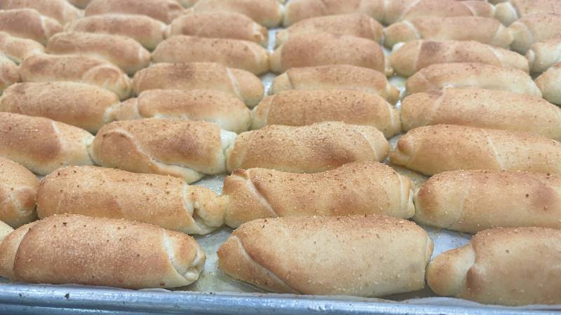 A sheet pan of señorita bread—dozens of the pillowy oblong rolls.