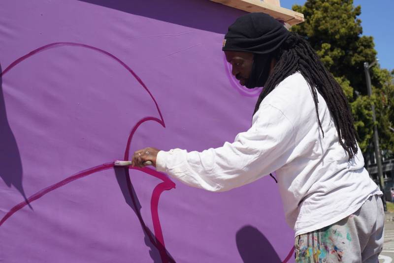 Malik Seneferu works on a mural in Oakland's Chinatown.