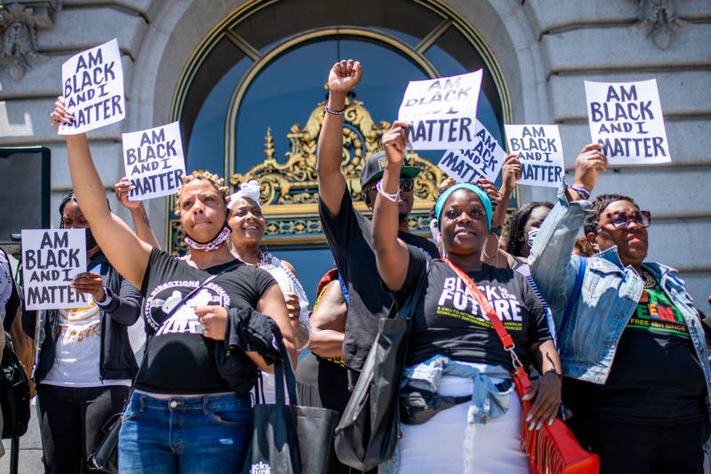 Attendees raise their fists and hold signs that say, "Am Black And I Matter" during a Juneteenth kickoff rally on the steps of San Francisco City Hall on June 17, 2021.