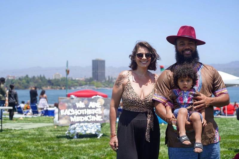 Leila Williams, Calvin Williams and their son Malik stop for a photo while standing in front of a sign that reads, "we are each other's medicine."