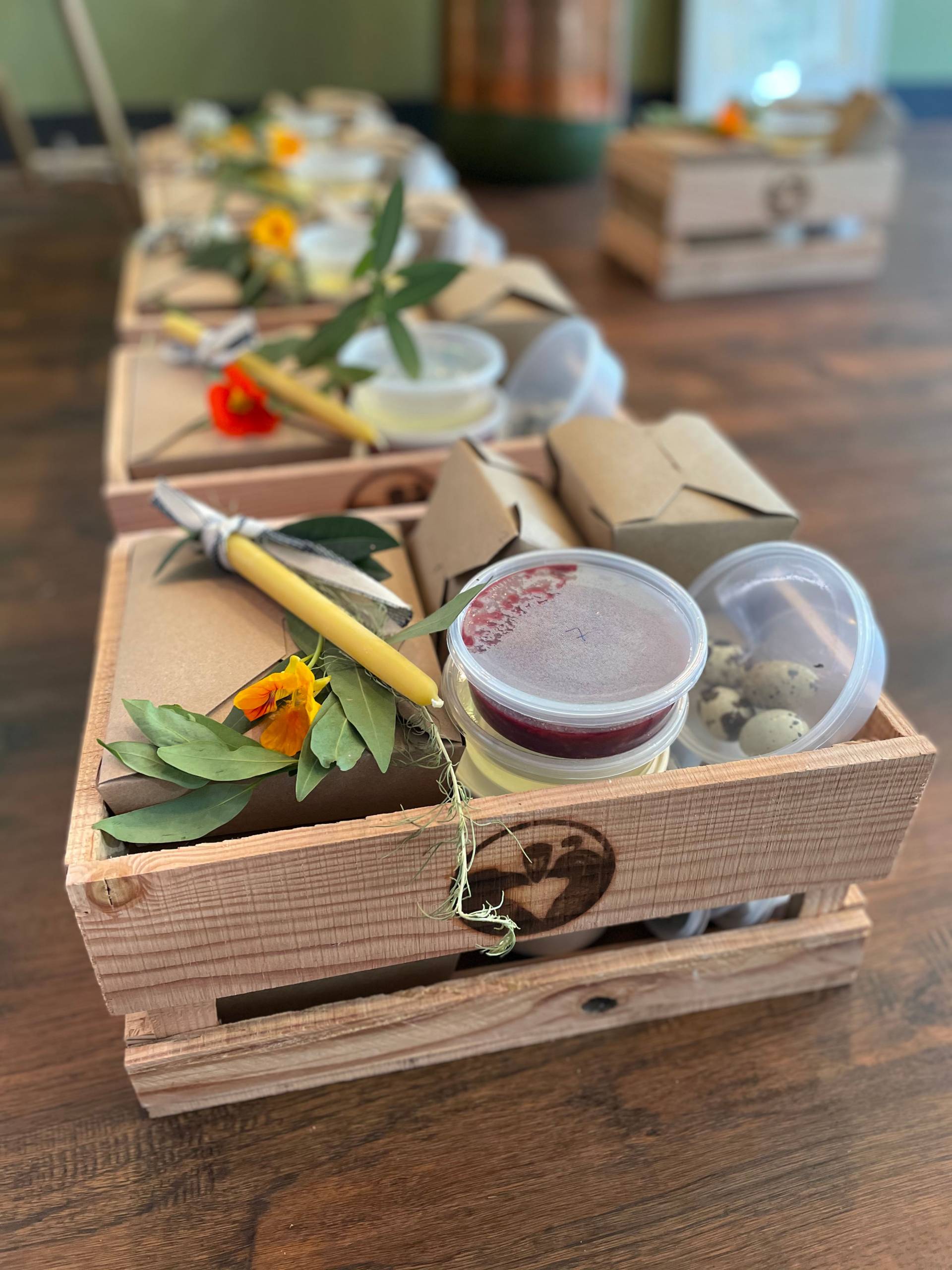 One of Cafe Ohlone's meal kits, packaged in a handmade wooden box, with fresh flowers and tubs of ingredients visible.
