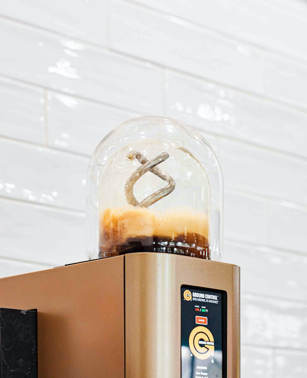 Close-up view of Ground Control's space age–looking machine, with coffee brewing in a clear glass cylinder on top.