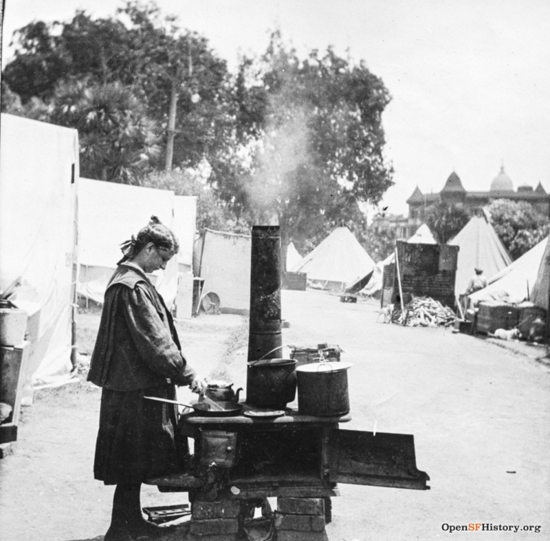 A woman using a makeshift stove in the Jefferson Square refugee camp. City Hall's dome can be seen in the distance. 