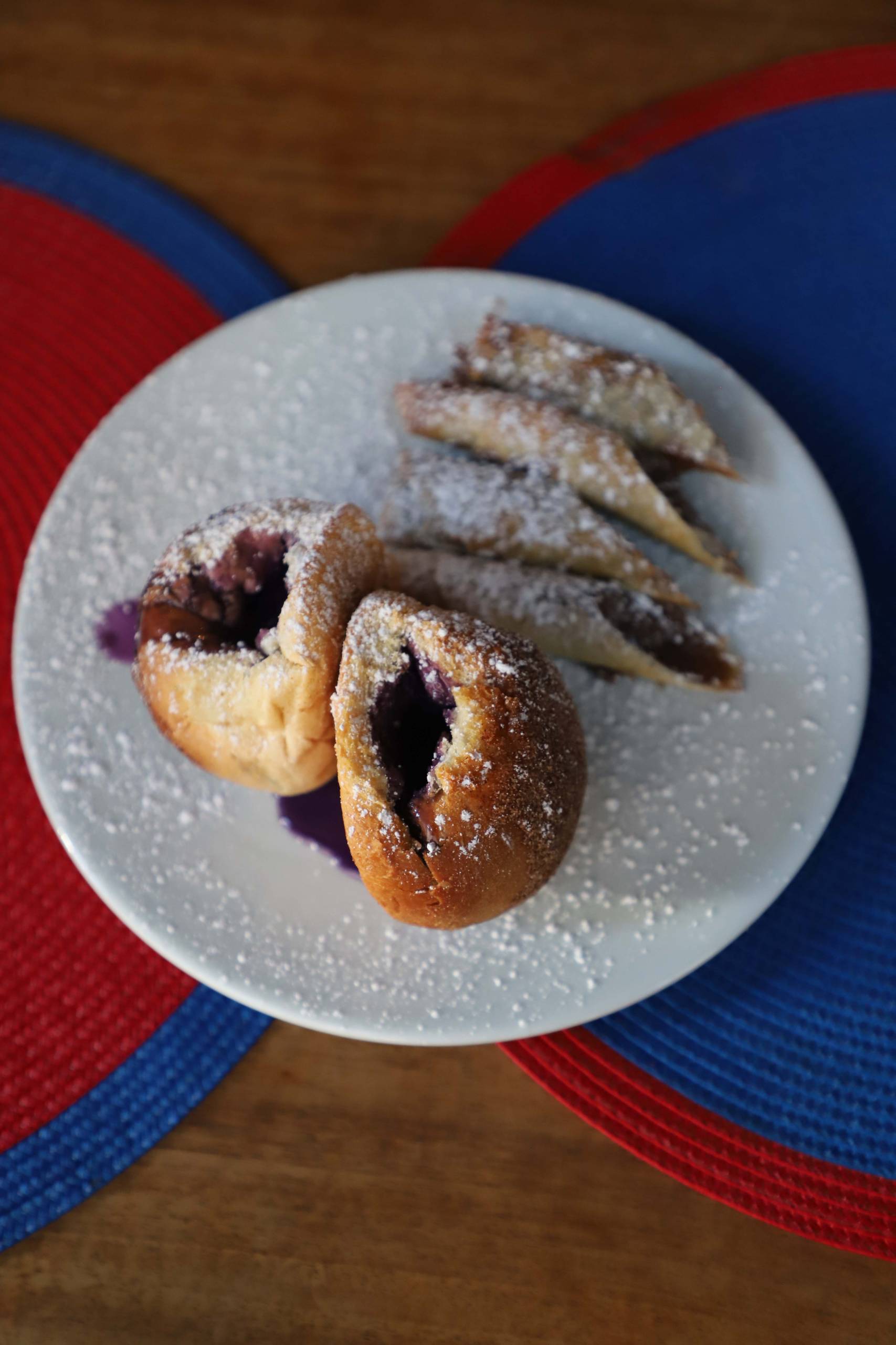 Ube buns and Milo banana creme lumpia on a white plate, dusted with powdered sugar.