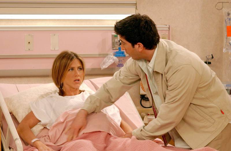 A pregnant Rachel (Jennifer Aniston) lies in a hospital bed, with Ross (David Schwimmer) at her bedside..