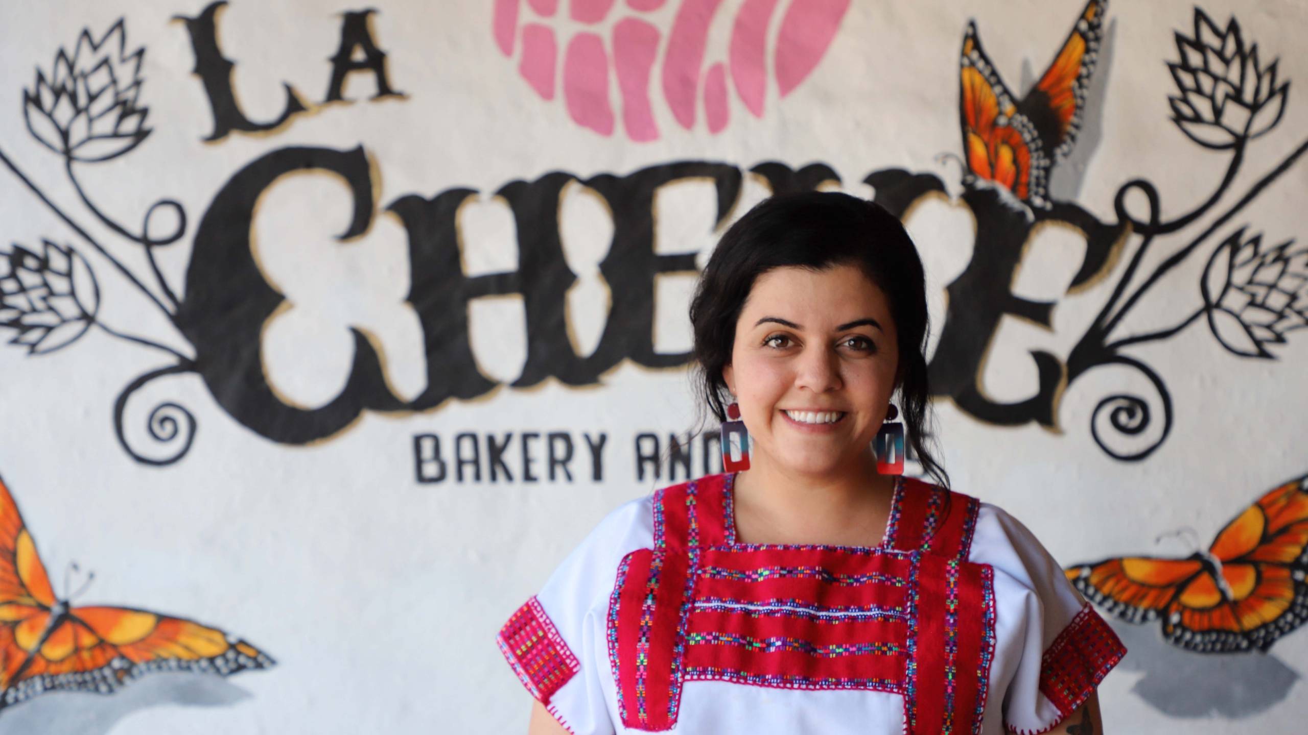 Cinthya Cisneros poses in front of the sign for her Napa restaurant La Cheve.