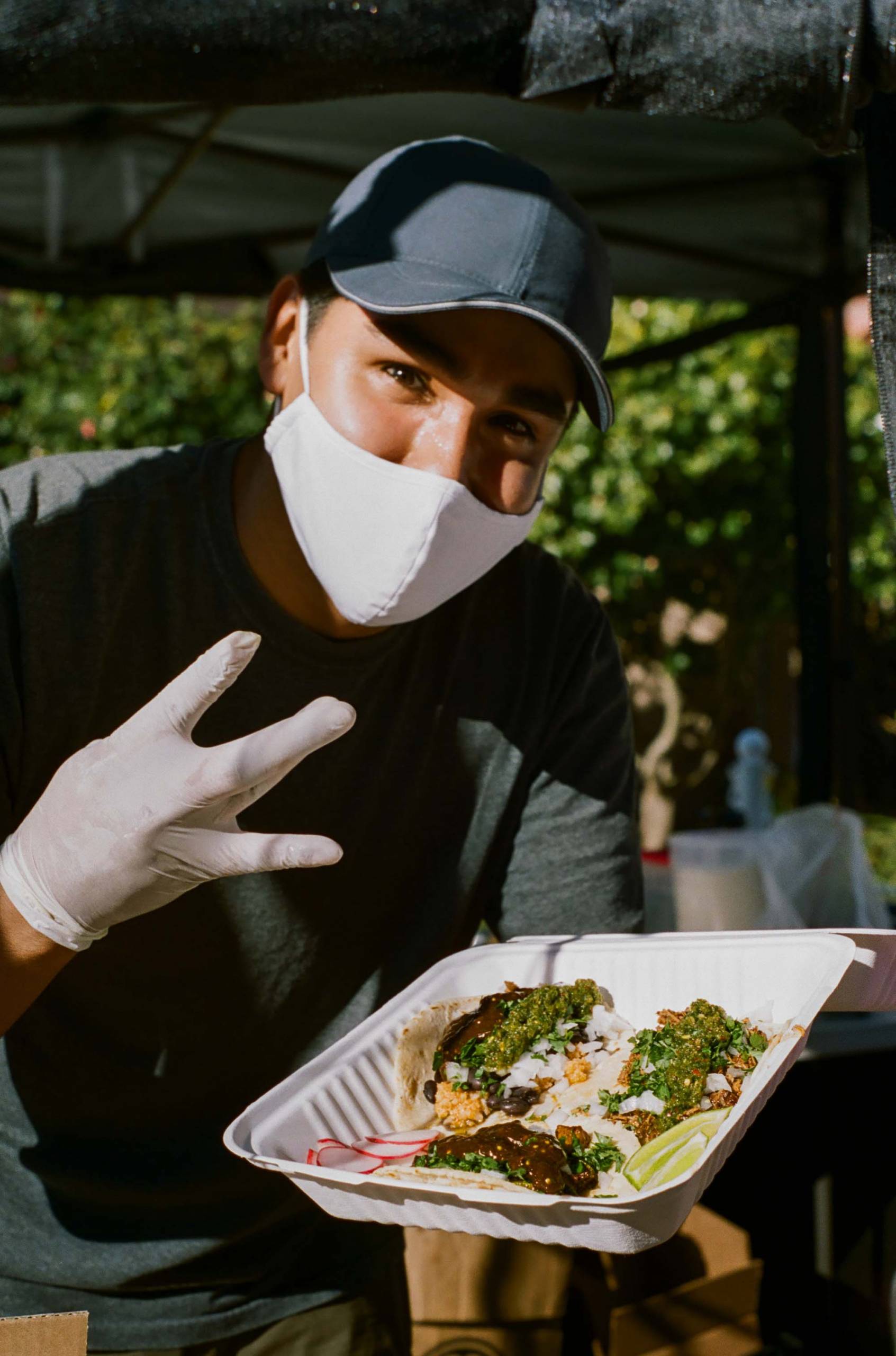 Nomar Ramirez serves up a box of tacos at his farmers market stand in the Outer Sunset