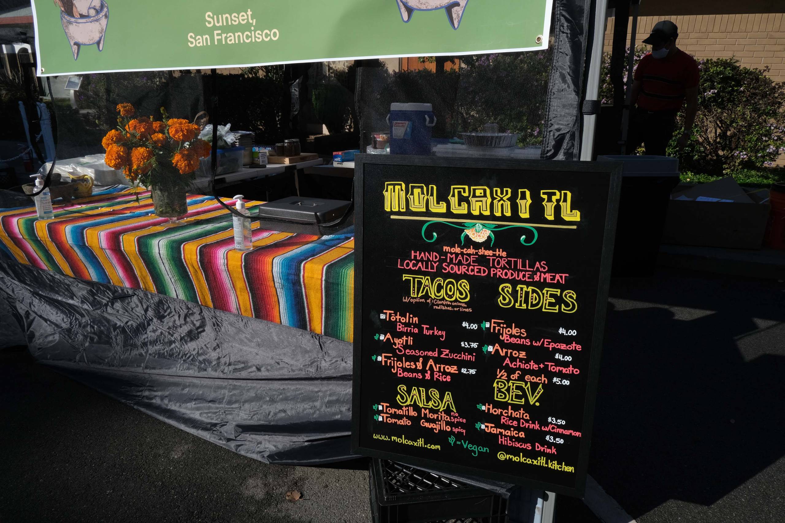 The menu board for Molcaxitl set up in front of the Outer Sunset farmers market stand