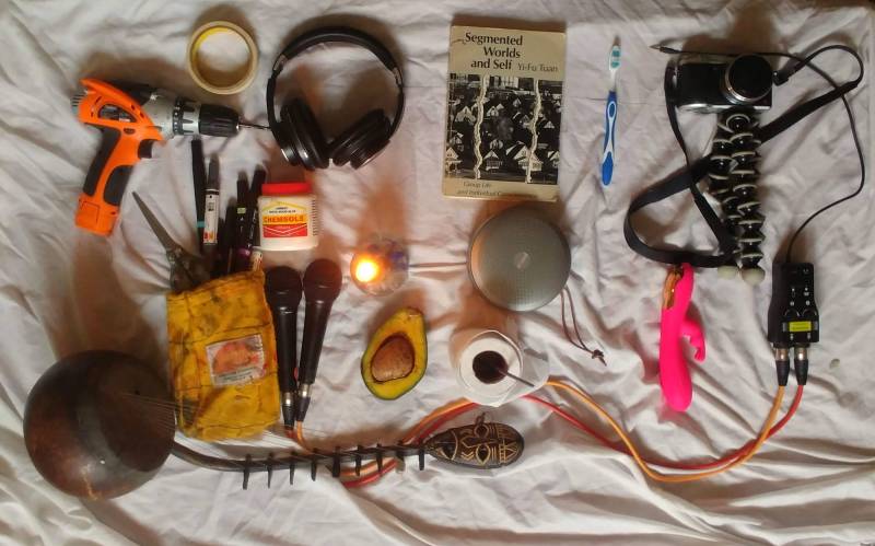 Items left to right: Drill, masking tape, headphones, collage-making supplies, microphones, kora (a type of lute), avocado, toilet paper, speaker, book, toothbrush, camera, vibrator.