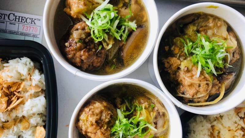 Braised meatballs in three round serving dishes, served with a side of rice.