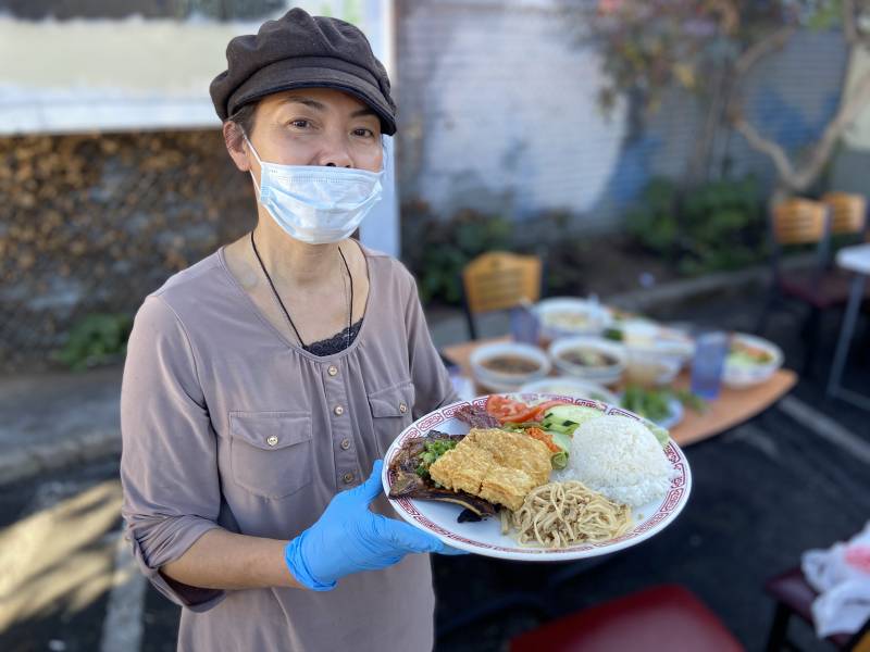 The owner of Mekong Restaurant holding a plate of Vietnamese food.