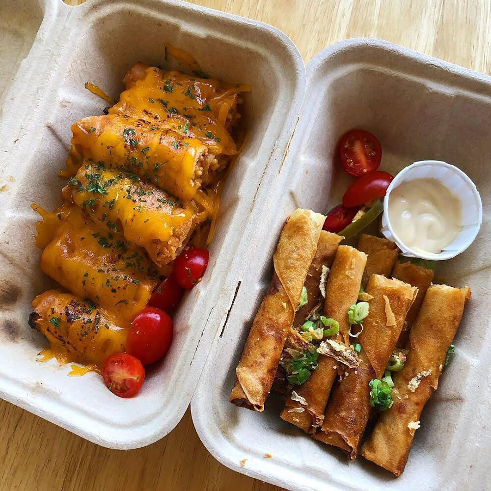 Two different kinds of lumpia in a cardboard takeout container.