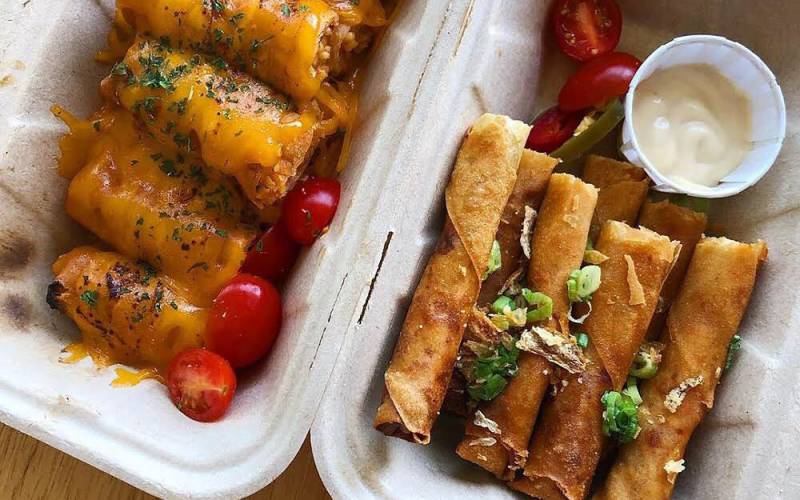 Two different types of lumpia in a cardboard takeout tray.