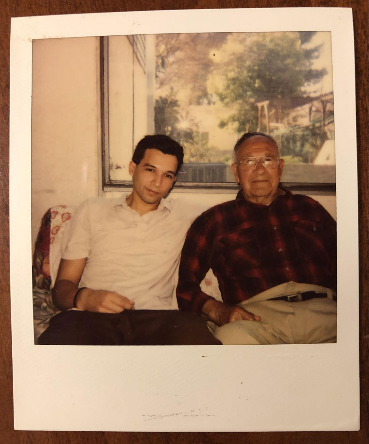 A younger man and an older man sit on a couch together.