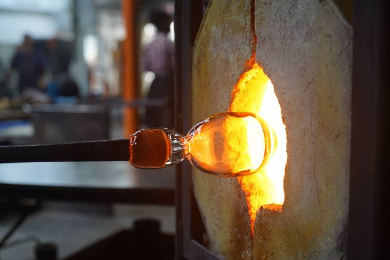 Taking some molten glass out of a fiery glory hole in preparation to mold it into a a beautiful object.