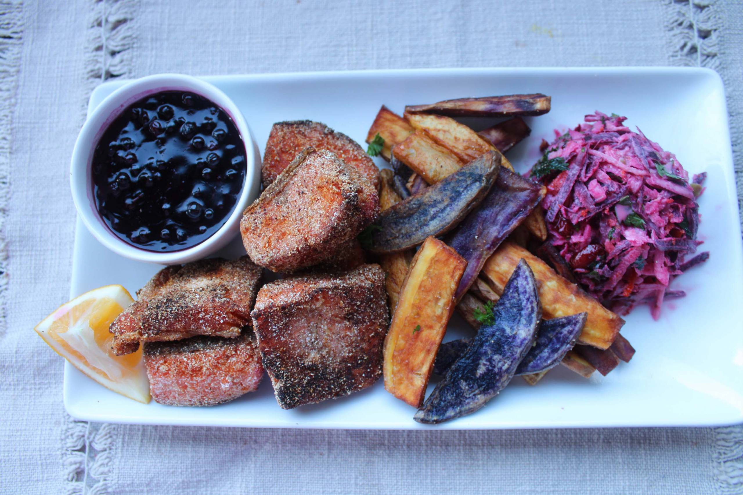 A plate of fried salmon and sweet potato fries, with berry sauce for dipping.