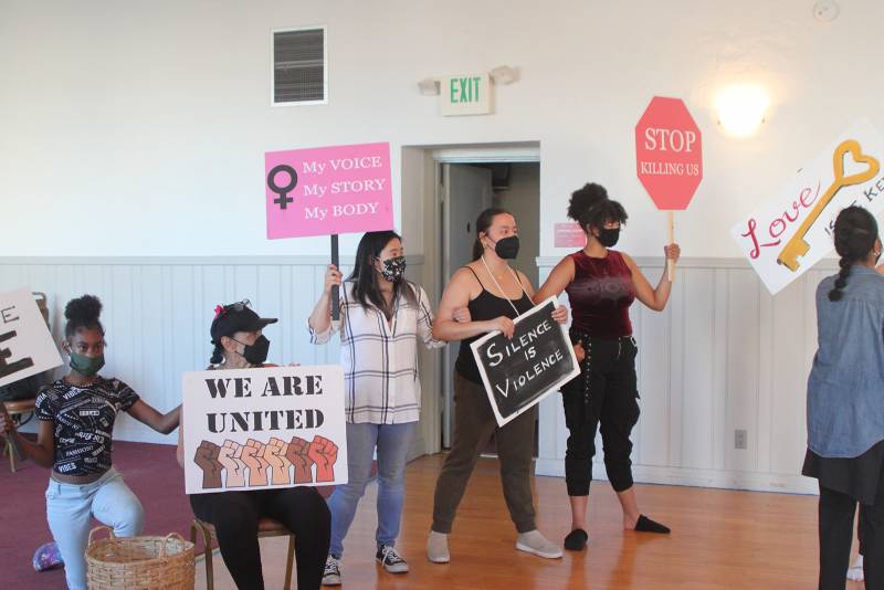 Singers in rehearsal hold protest signs.
