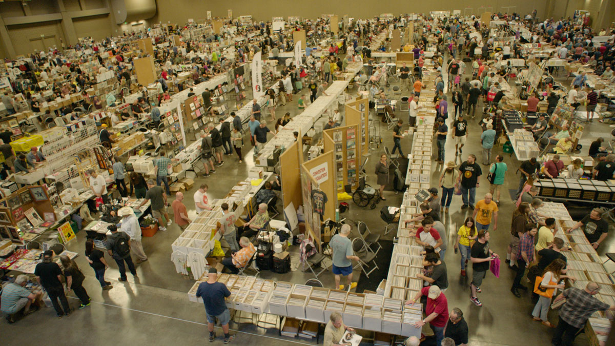 A huge crowd in a warehouse browses records.