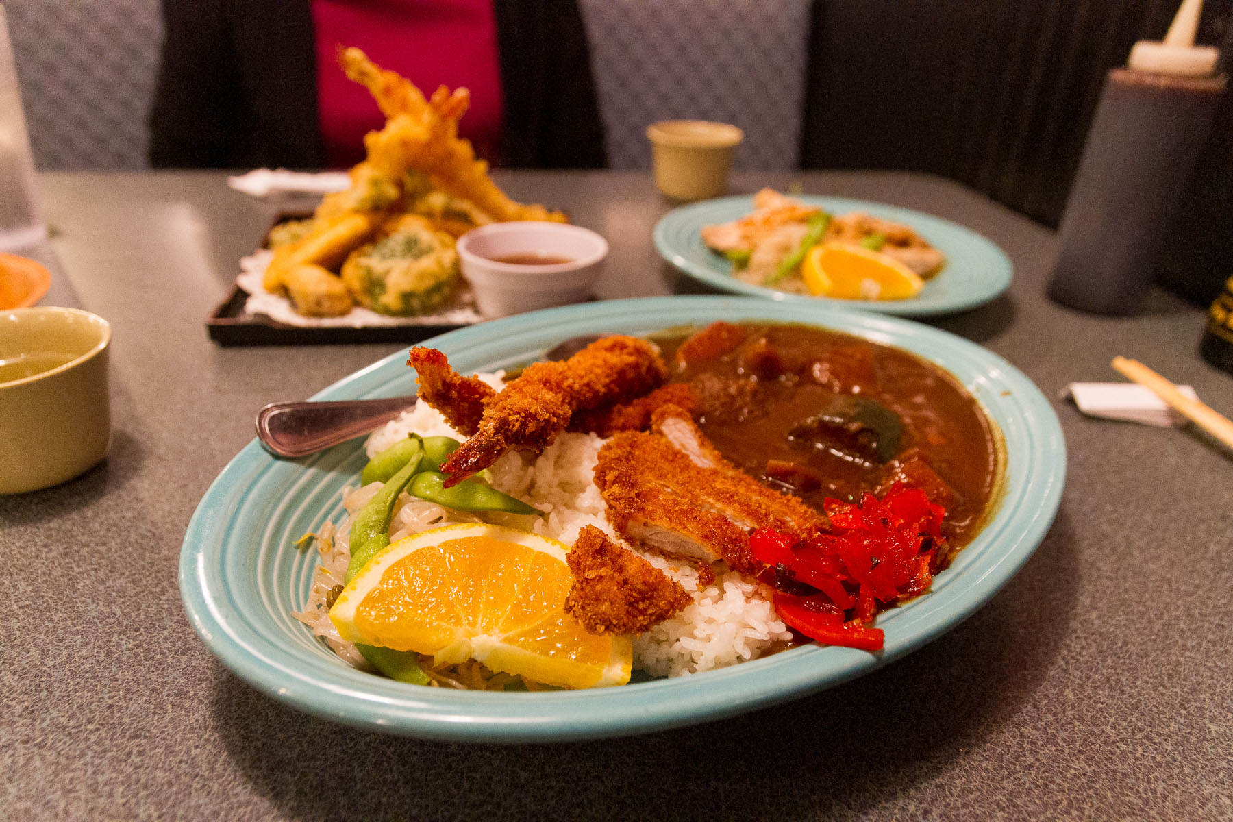 A spread of homey Japanese dishes; a plate of Japanese brown curry over rice is in the foreground.