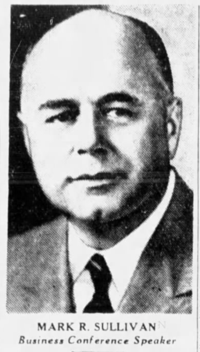 A bald white man with a round face wearing a suit and tie appears in newsprint.
