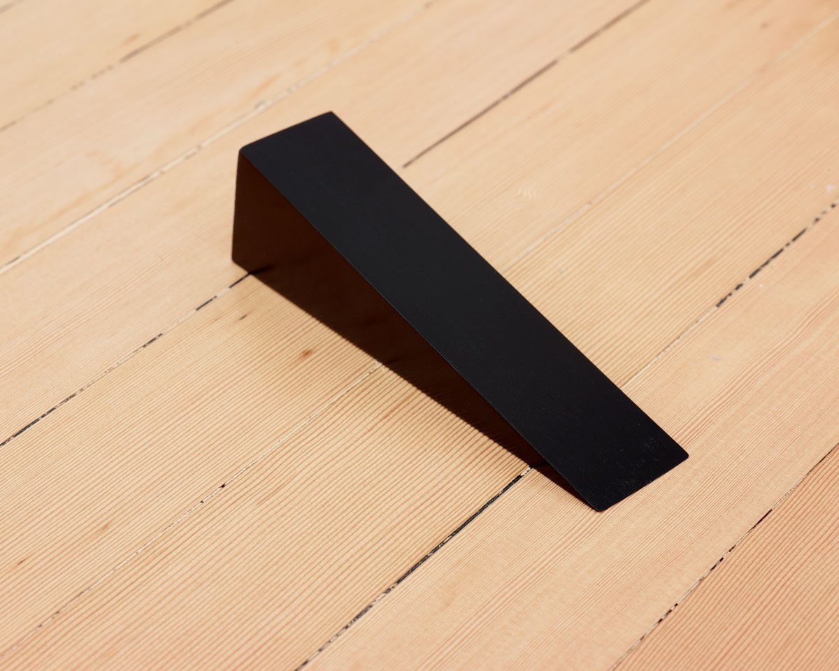 A black wedge on a light wood floor.