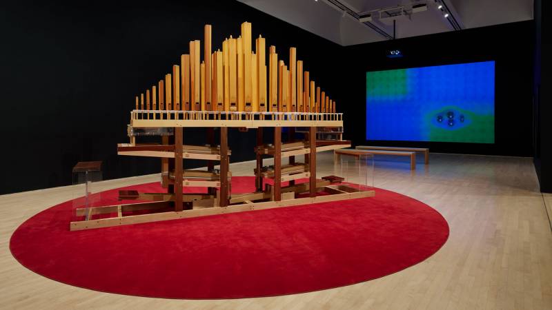 A wooden organ-like instrument on a red circle of carpet