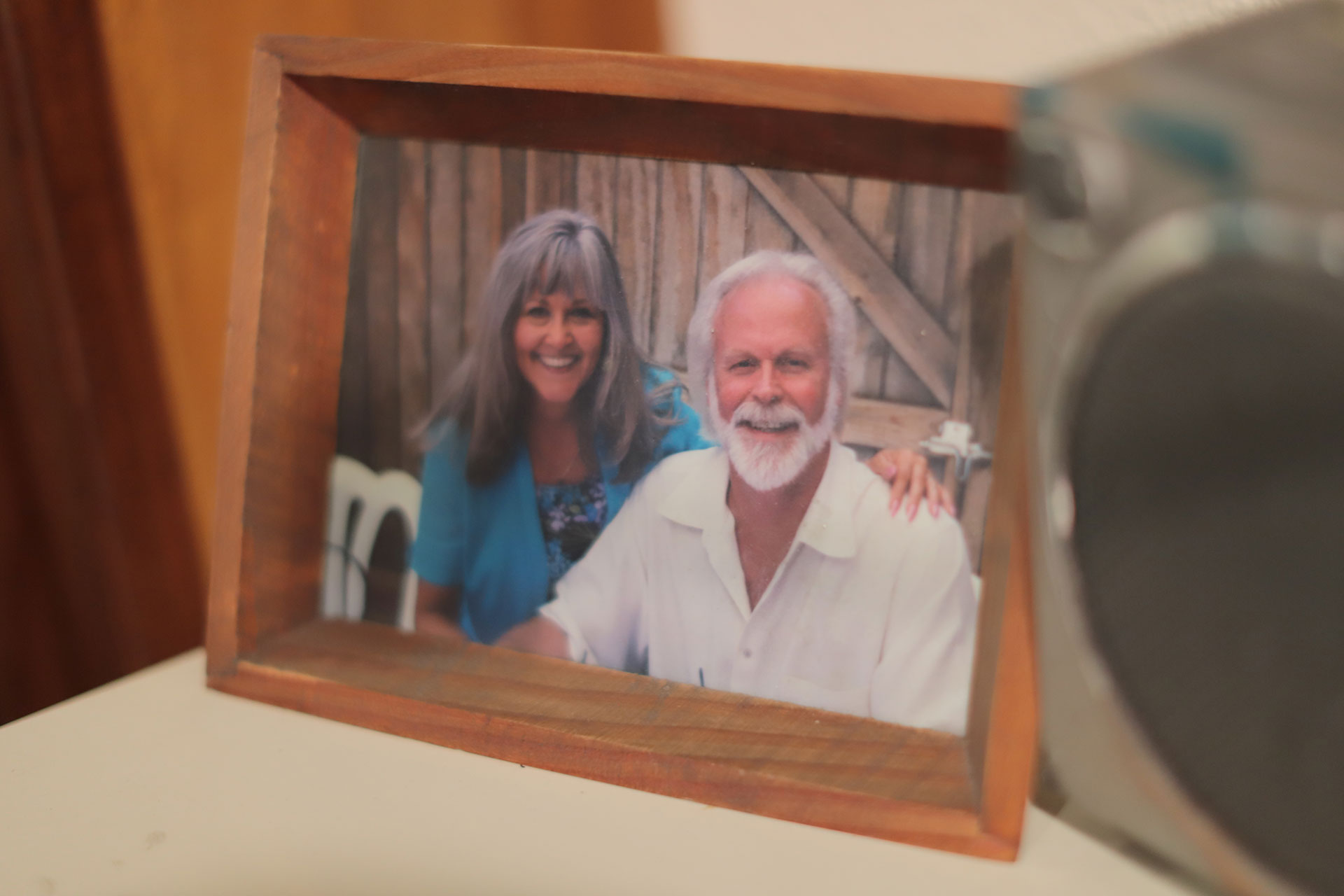 A man and a woman embrace in a photo in a wooden frame next to a boombox.