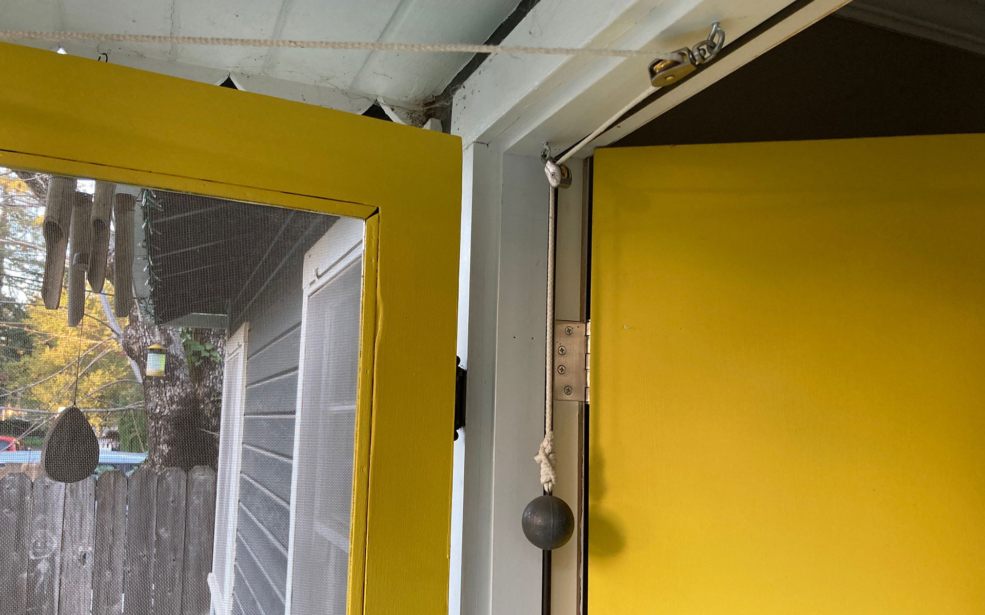 a rope-and-pulley contraption attached to a yellow screen door