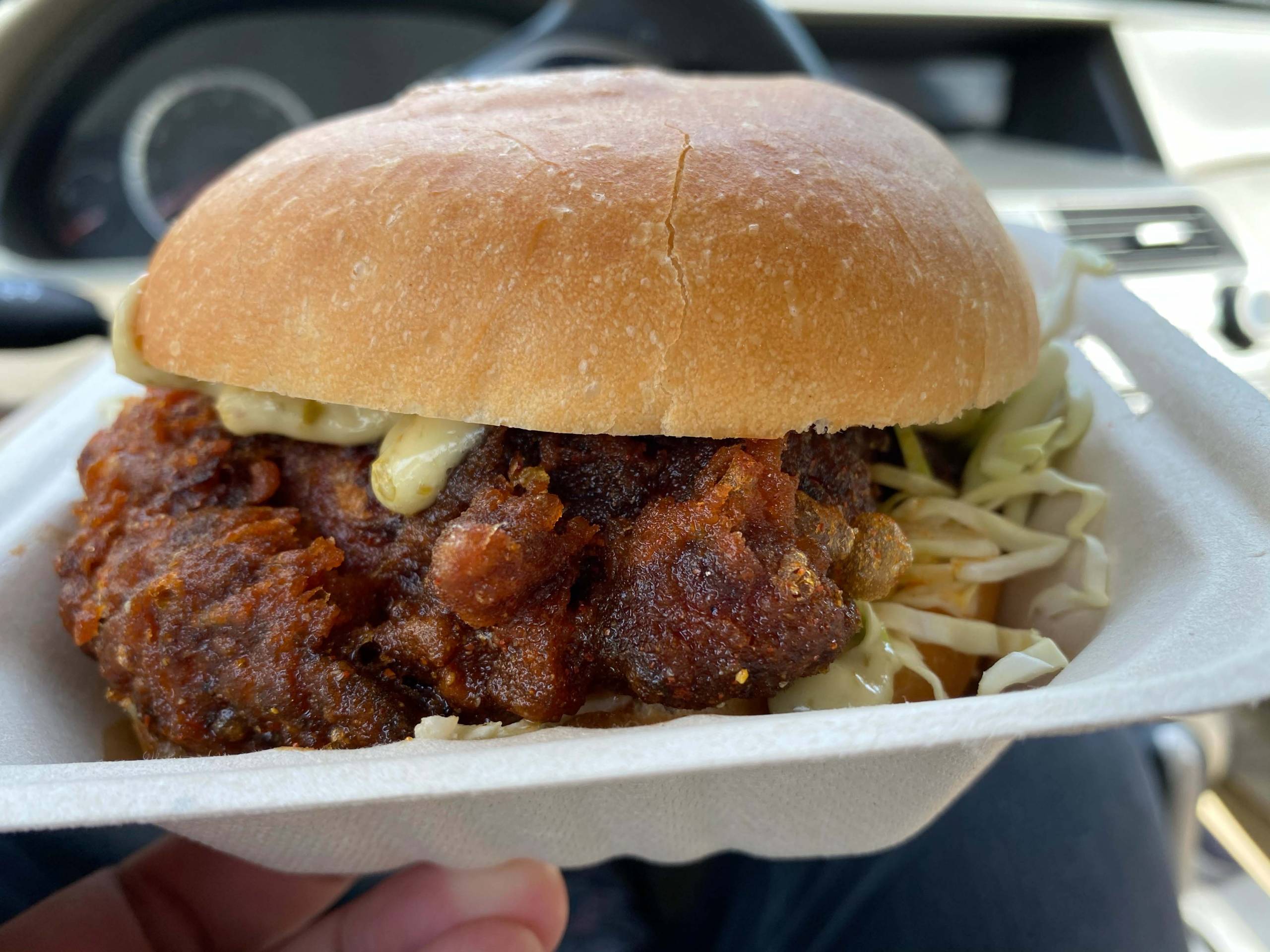 A fried chicken sandwich in a plastic takeout container.
