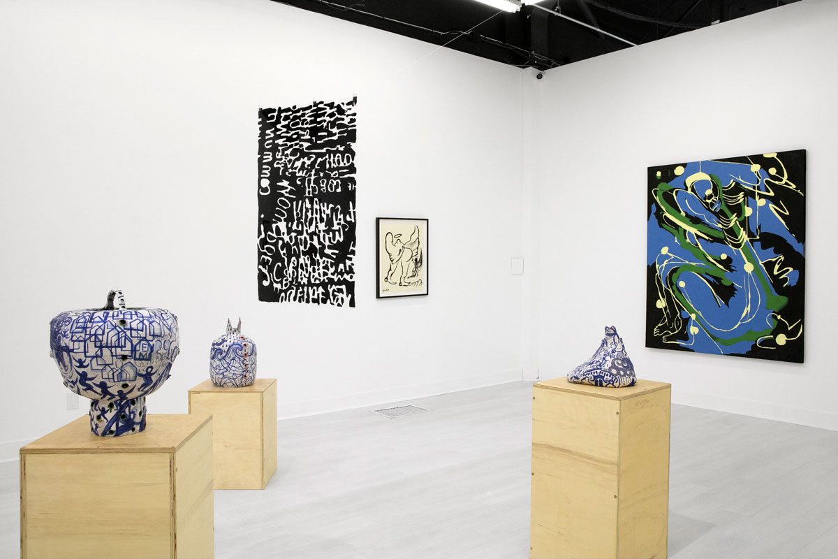 Sculpture on wood pedestals, a hanging text piece, a black and white drawing and a large blue and black painting.