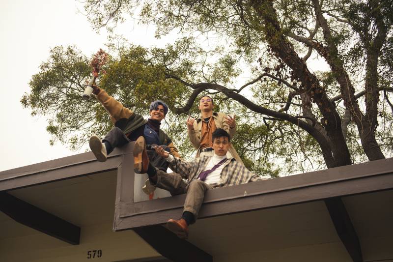 Three Asian American hip-hop artists hang out on a roof top.