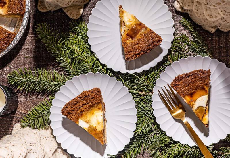 Slices of a custard pie on plates, laid out on top of a Christmas-themed evergreen tree backdrop.