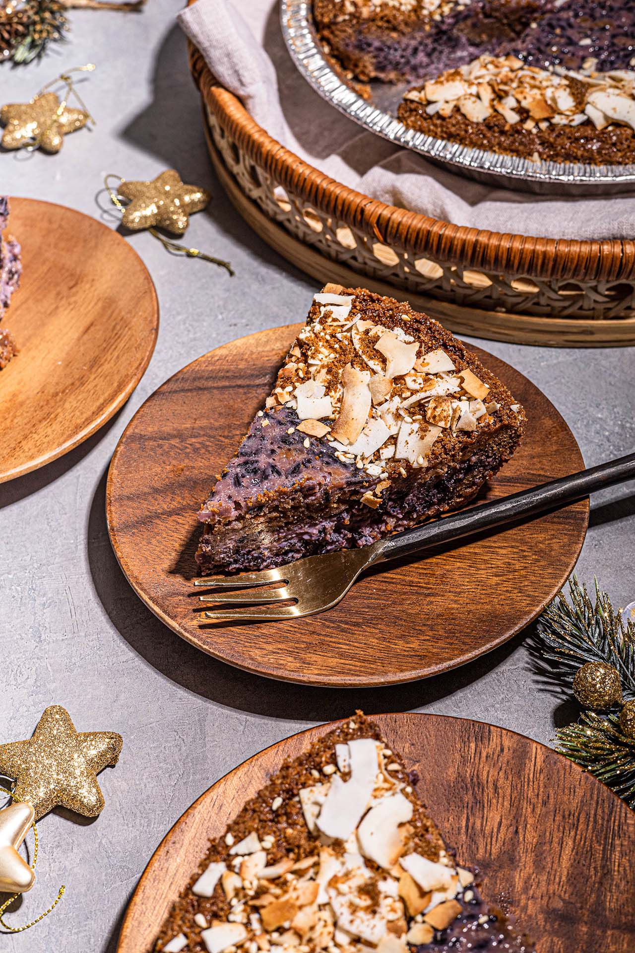 Slice of purple pie topped with shaved coconut on wooden plate.