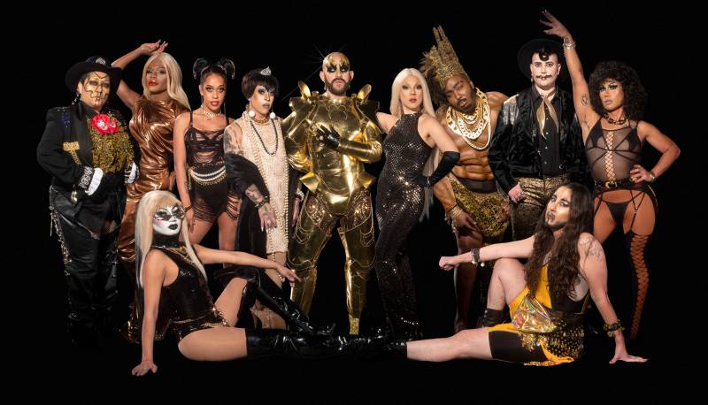 A group photo of drag performers of different genders dressed in black and gold.
