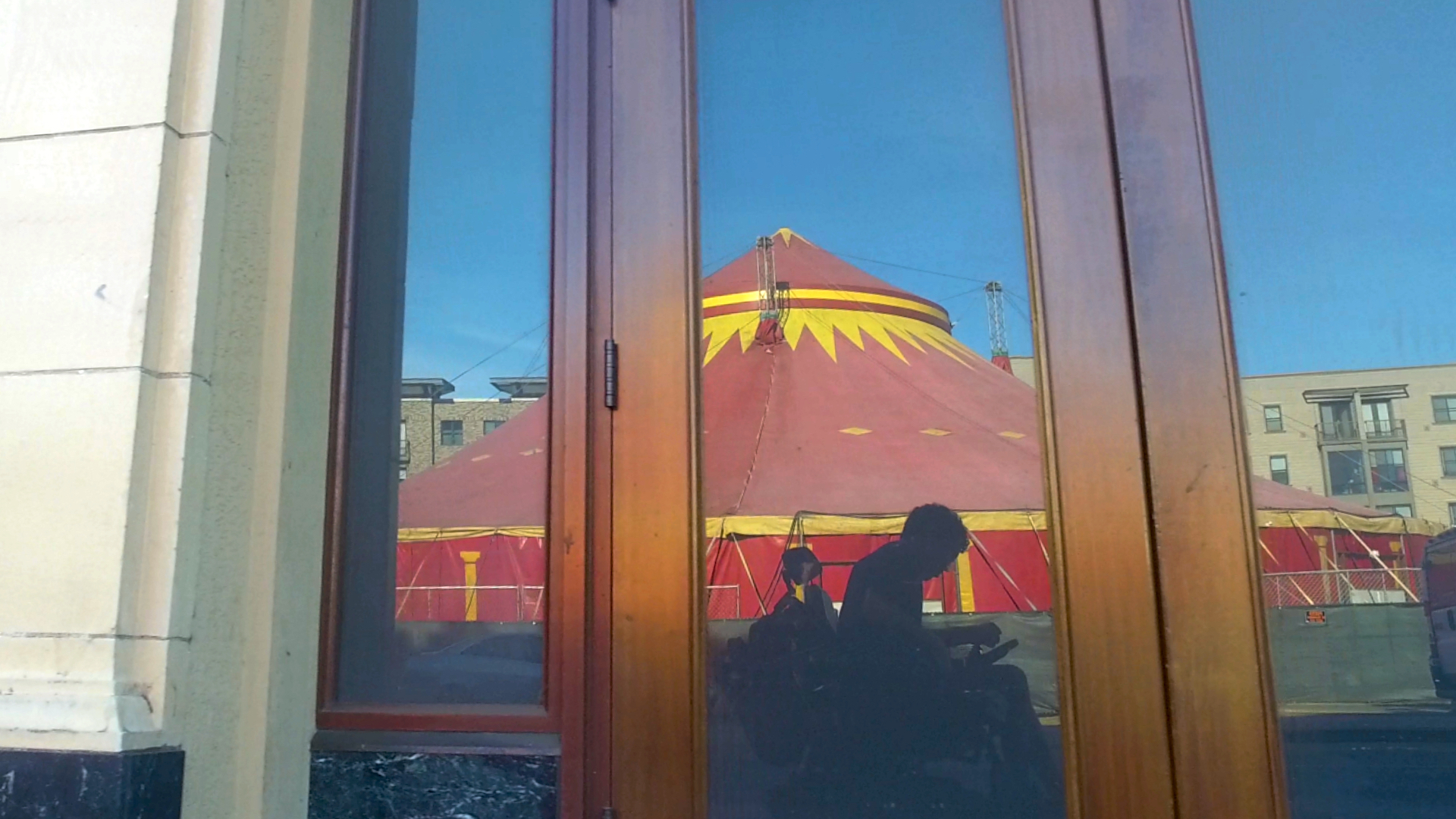 Reflection of circus tent and person in wheelchair in window