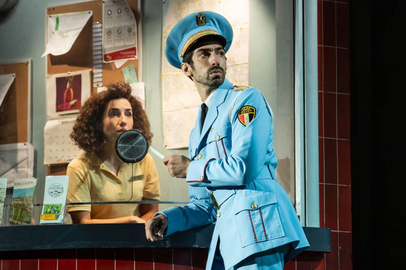 A scene from 'The Band's Visit' Broadway play, where Joe Joseph is in costume as a military band member and Layan Elwazani plays a box office clerk.