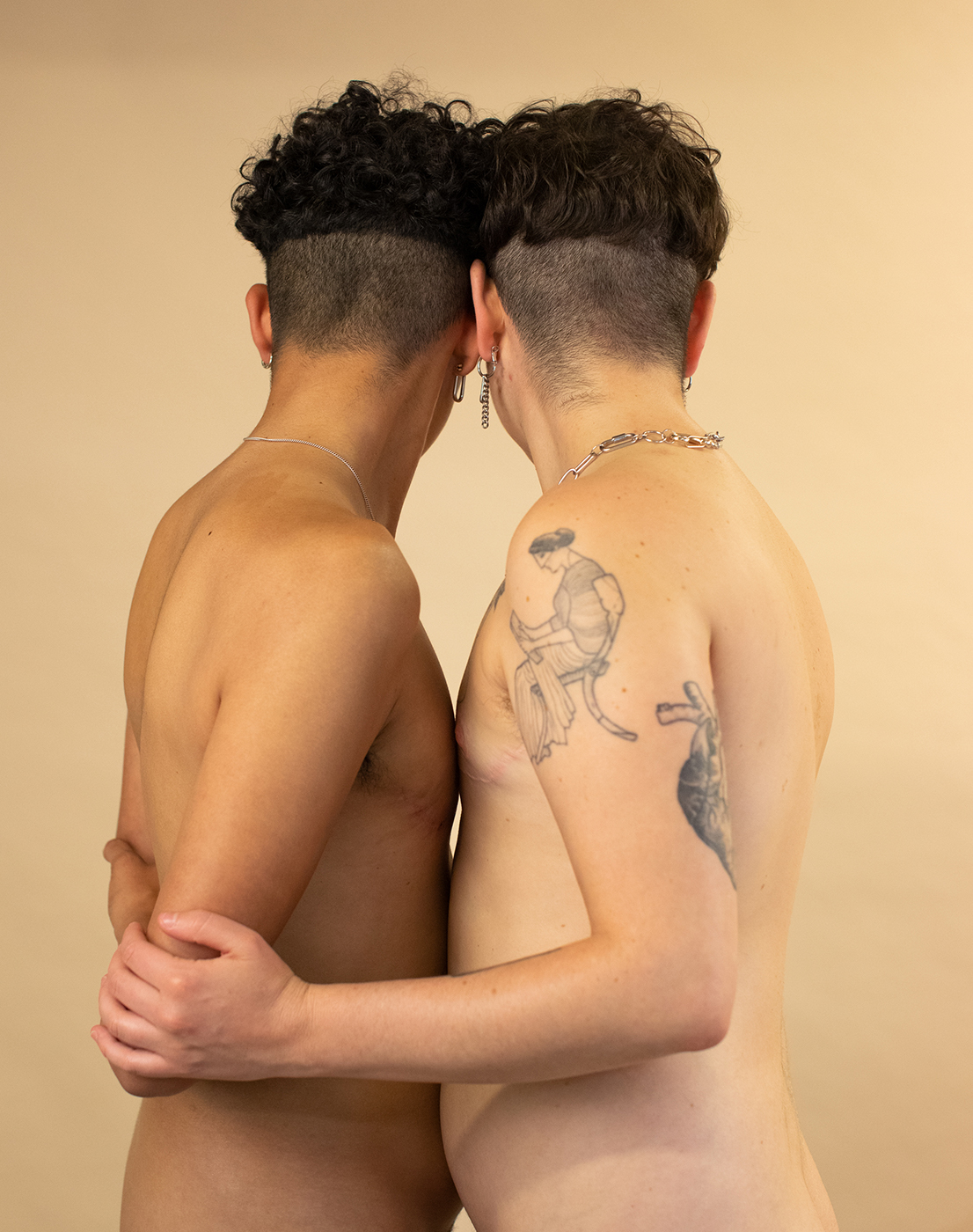 Two figures embrace, shirtless, heads turned away from camera