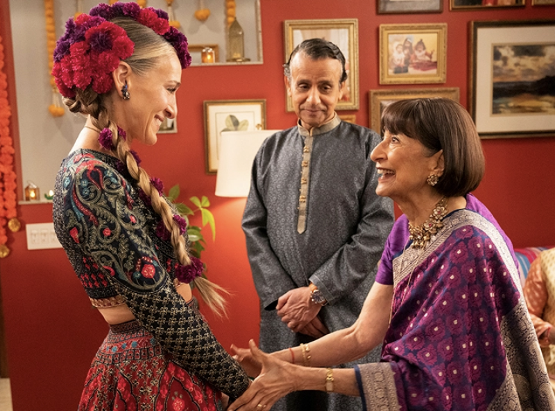 Carrie Bradshaw, played by Sarah Jessica Parker, wearing traditional Indian clothing and greeting Seema's parents.