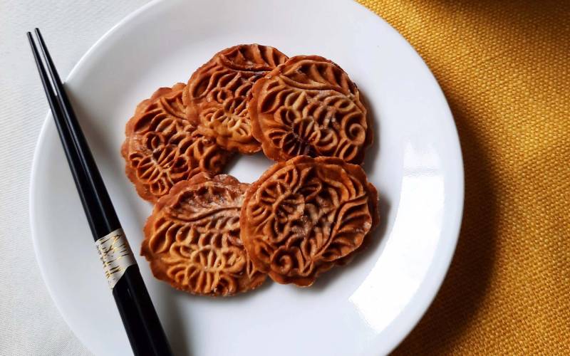 A plate of five mooncake biscuits with a traditional engraved pattern.