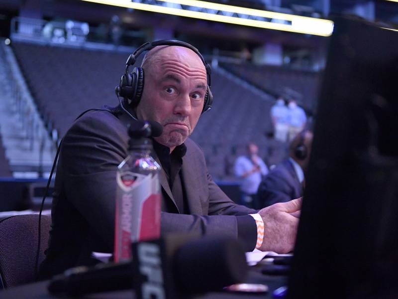 Joe Rogan, headphones on, sits behind a desk, making a goofy face for the camera.