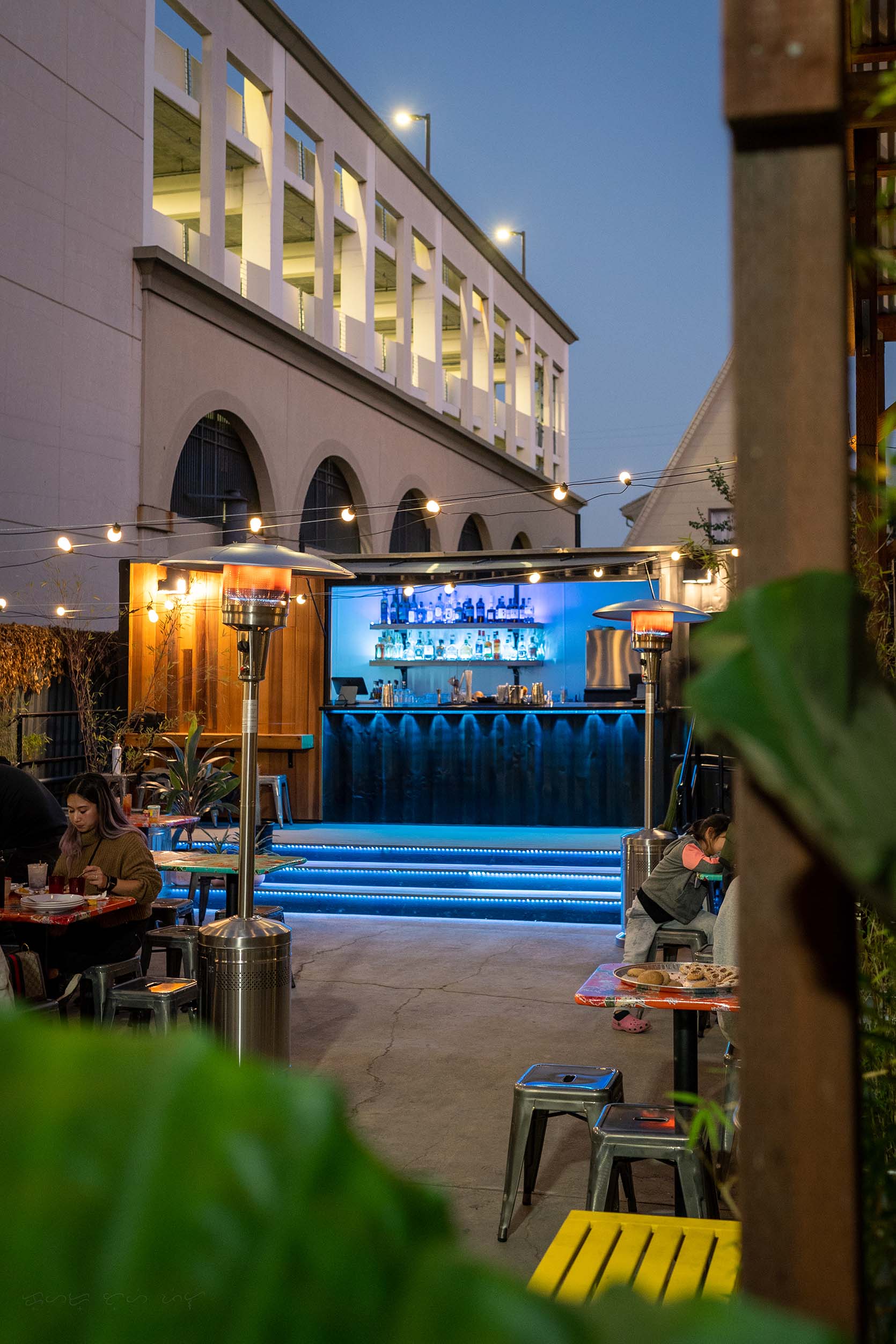 An outdoor bar lit up by blue neon lights with the Fruitvale BART station in the background.